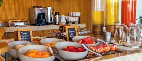 Un bufé de desayuno con diversas frutas y una estación de café.