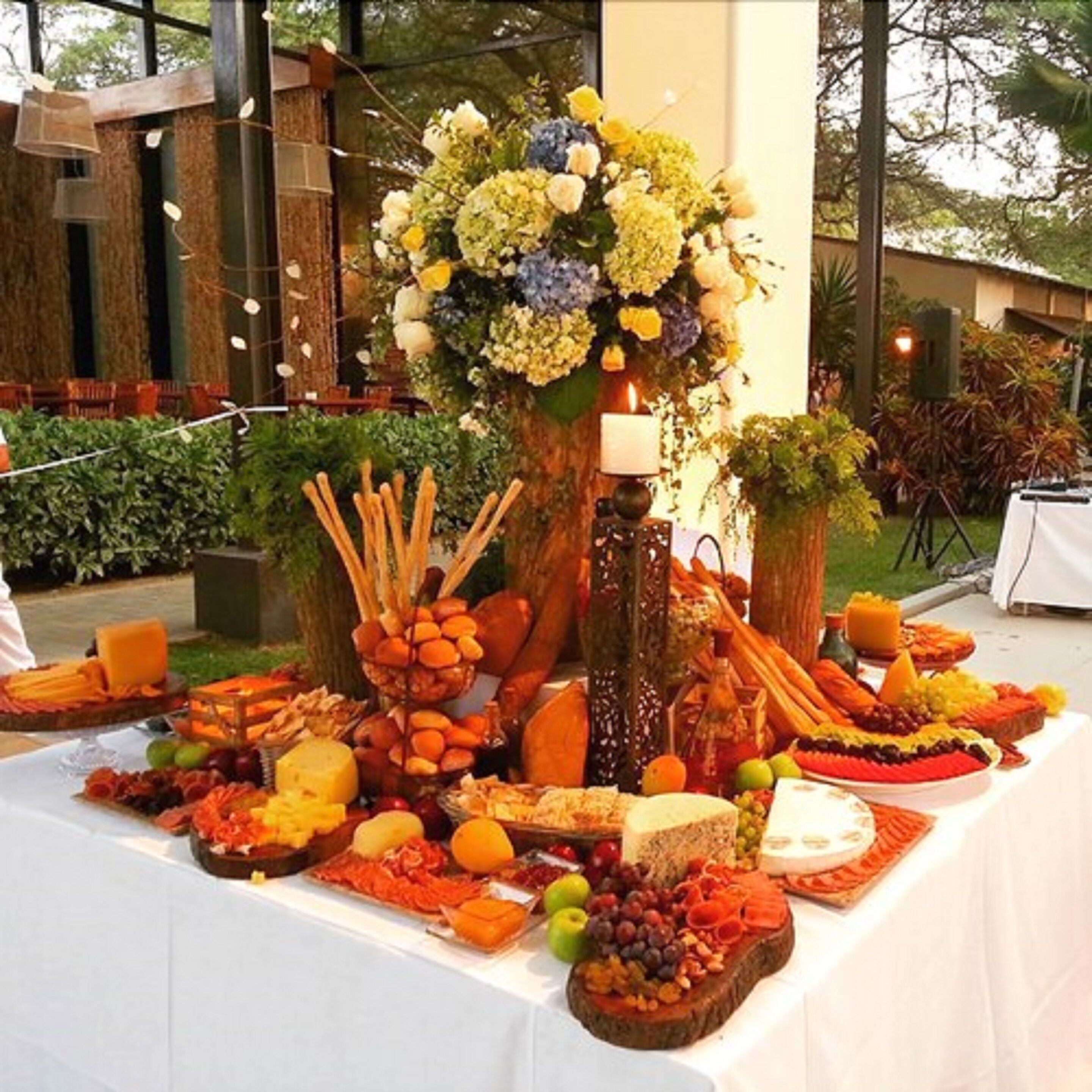 A buffet table with various food items and a floral centerpiece.