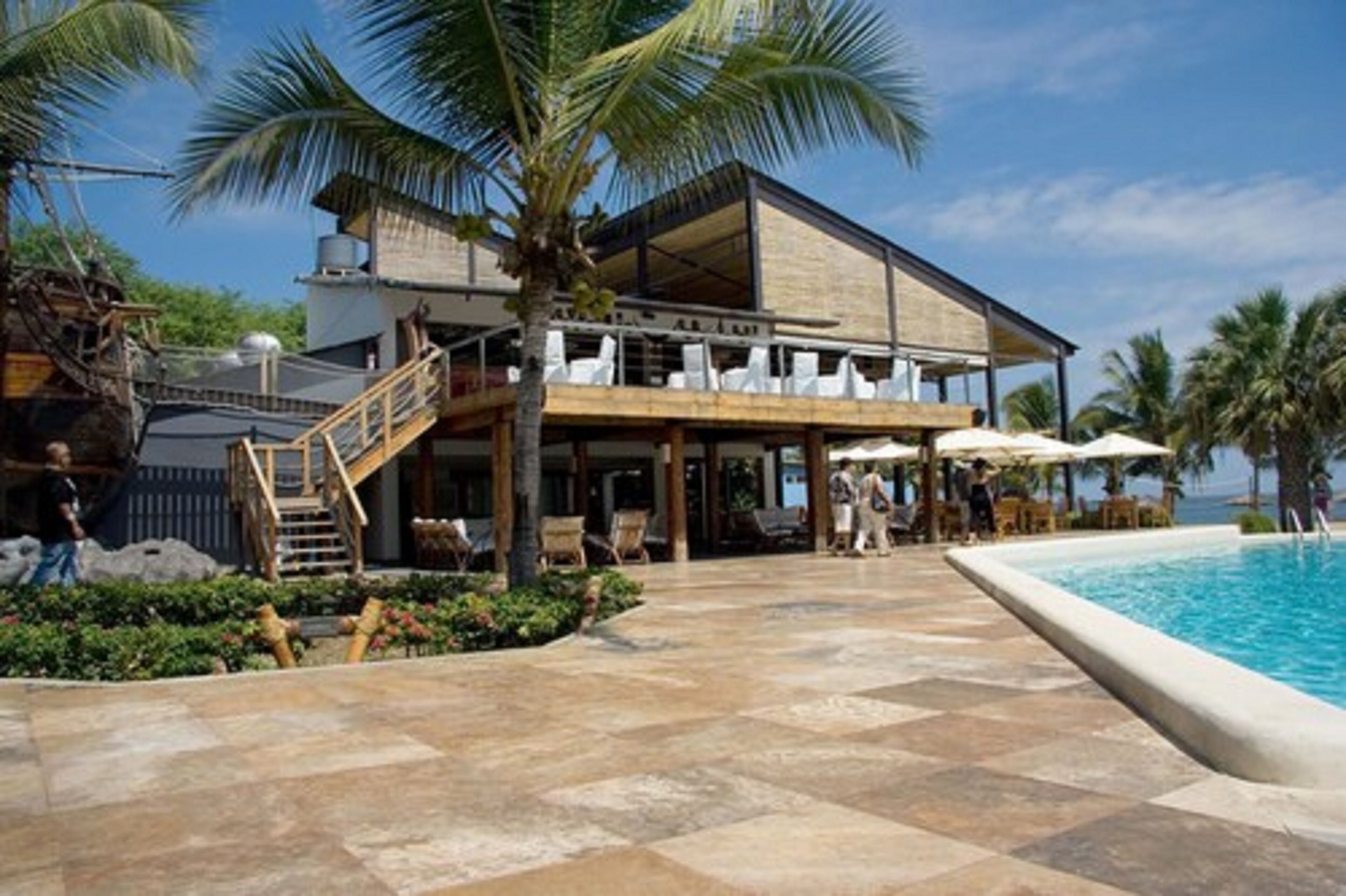 Un resort con piscina, mobiliario exterior y un edificio de dos pisos con balcón.