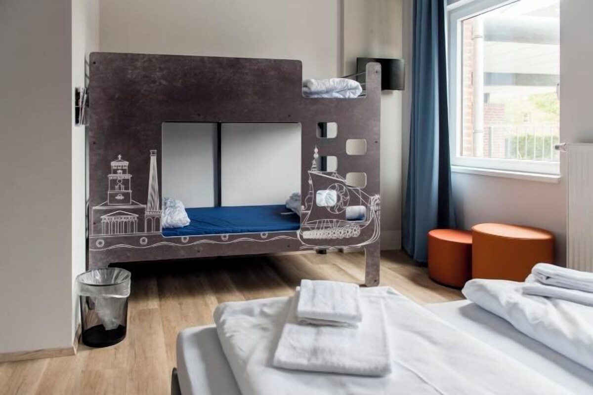 Un letto a castello con decorazioni, una finestra con tende e un cestino.