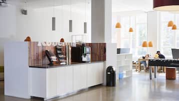 Eine moderne Küchenzeile mit einer zentralen Kochinsel, einer Kaffeemaschine und einer Sitzecke mit Tisch und Stühlen.