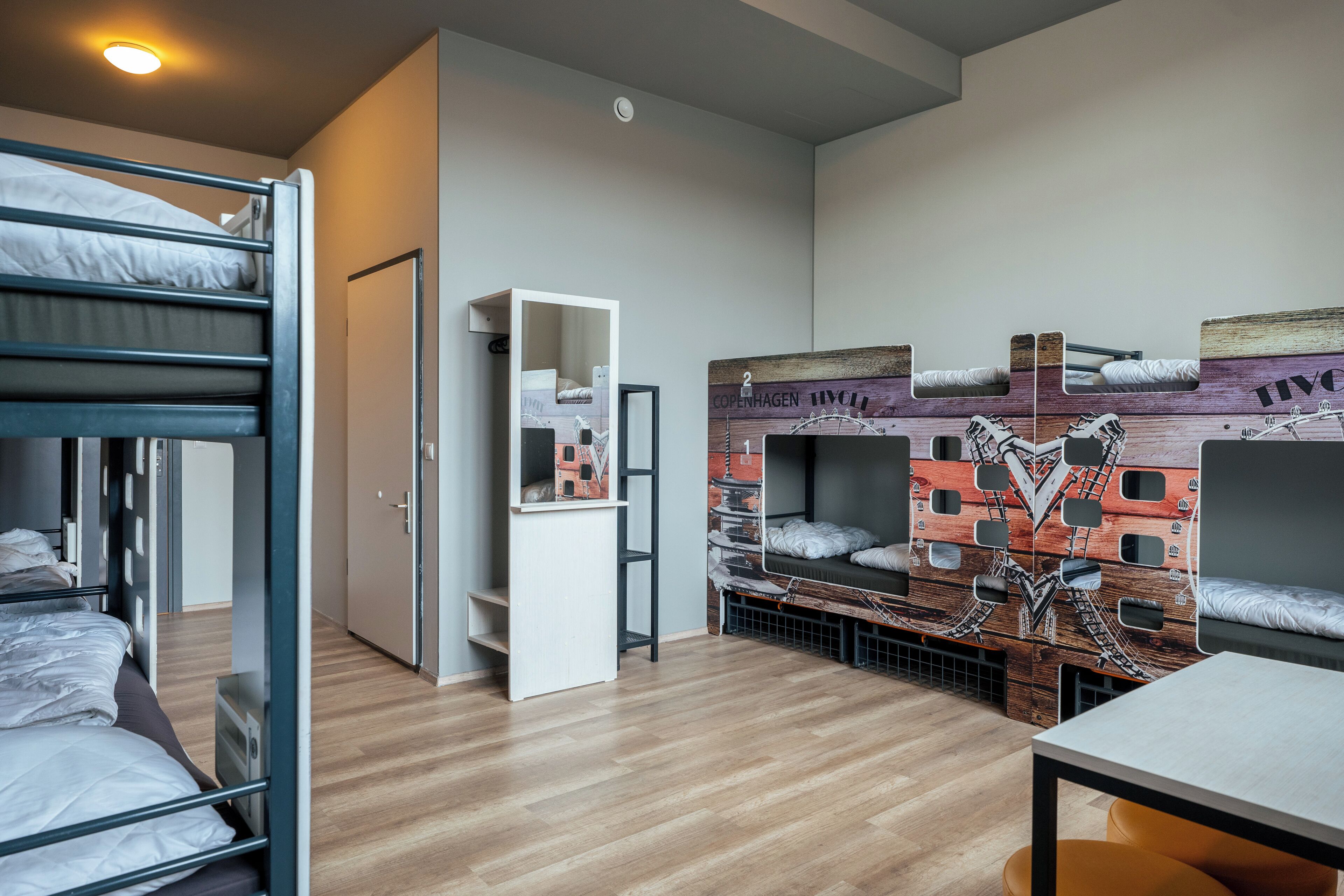 Une chambre de dortoir avec des lits superposés, une armoire blanche et une étagère fixée au mur.