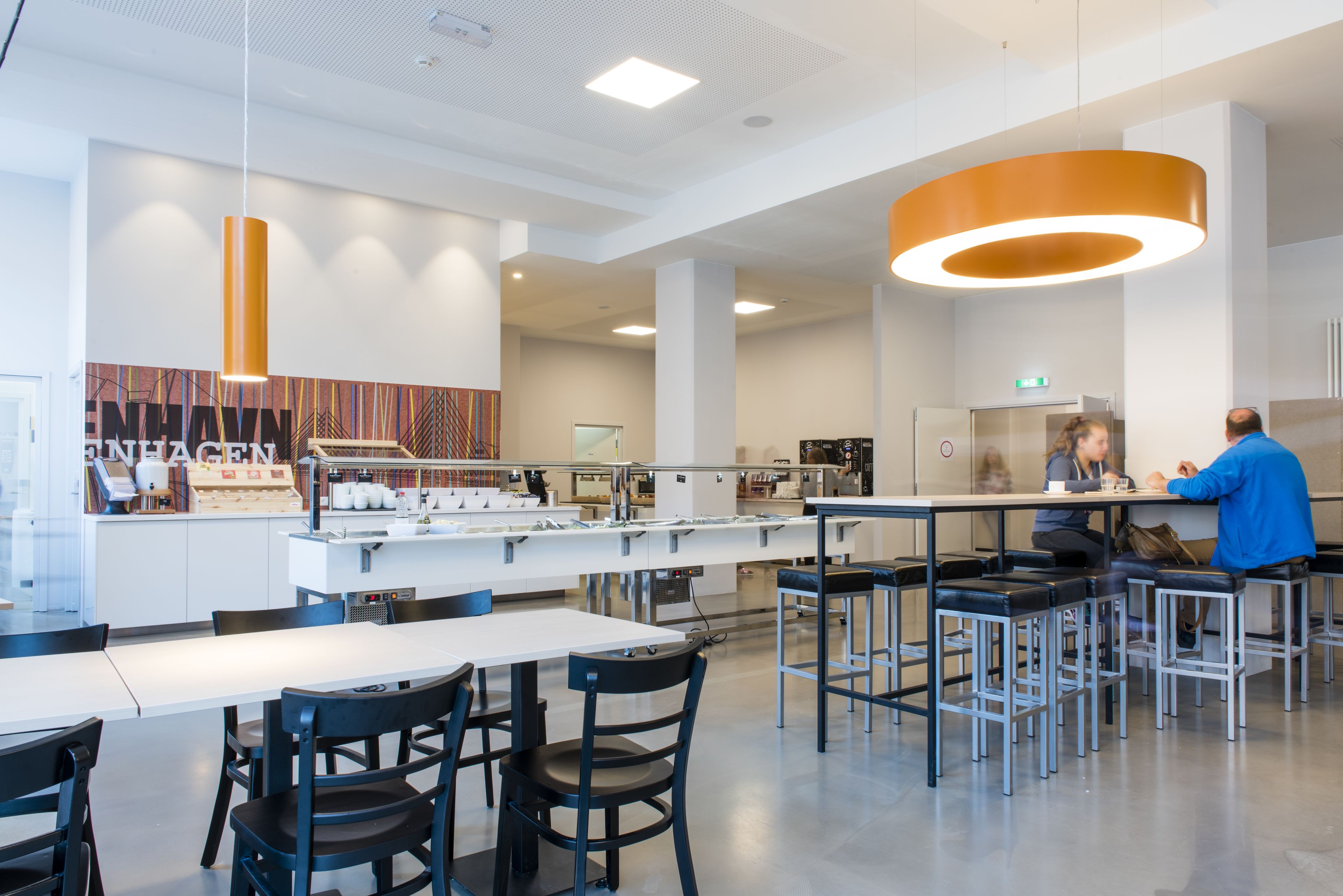 A modern restaurant with a central island, bar seating, and a bright pendant light.