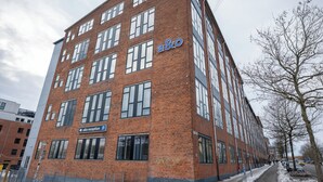 Un edificio de varios pisos de ladrillo con amplias ventanas, una recepción y un letrero de estacionamiento.