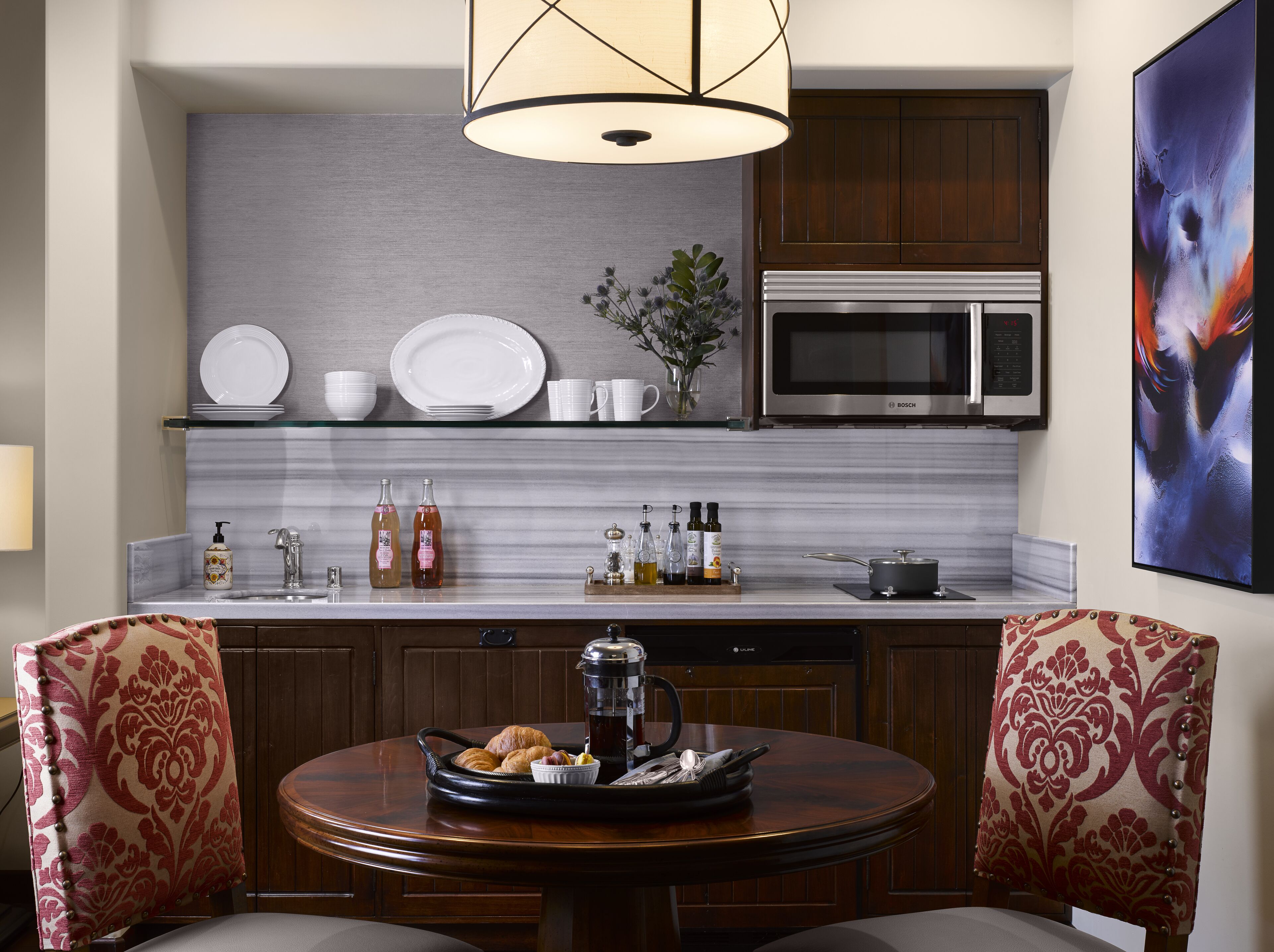 Una cocina moderna con un microondas Bosch, una cafetera y una mesa de comedor con sillas.