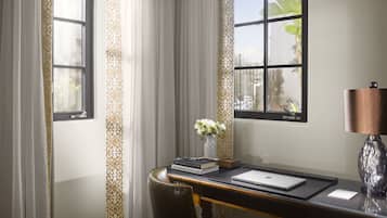 A desk with a laptop, books, and a vase of flowers.