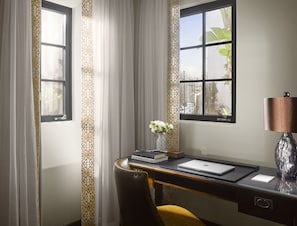 A desk with a laptop, books, and a vase of flowers.