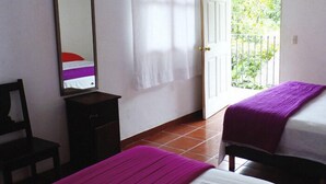 A room with two beds, a mirror, a small table, and a door leading to a balcony. - Finca Santa Mónica (Xilitla)