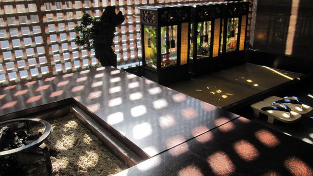 Une pièce avec une table en bois, un petit foyer et une cloison ajourée.