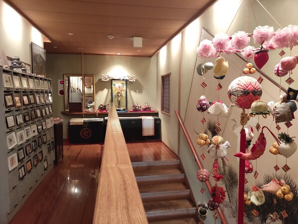 A hallway with a wooden bench, framed pictures on the walls, and a staircase with decorative hanging ornaments.