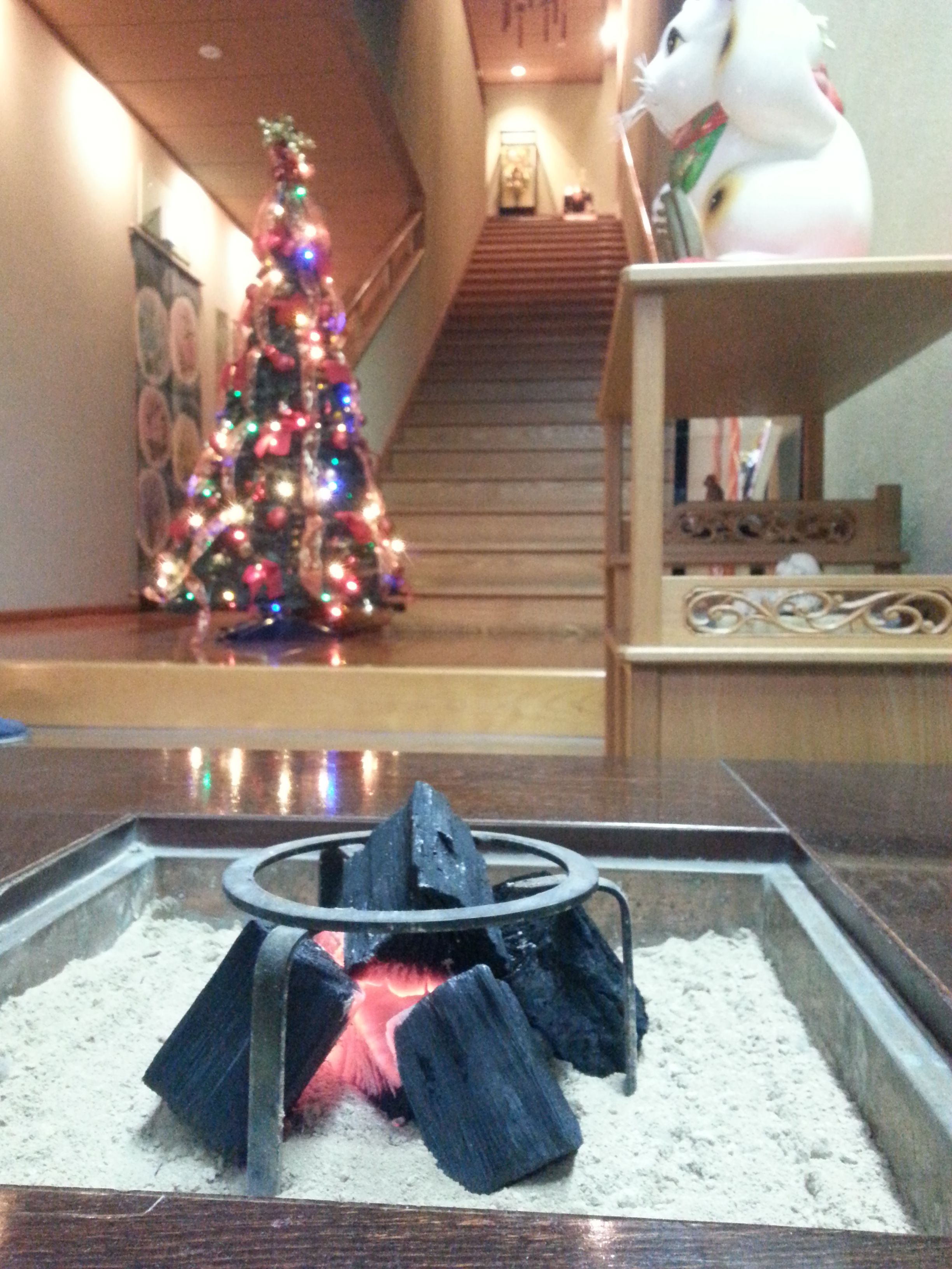A hotel lobby with a Christmas tree, a fireplace, and a staircase.