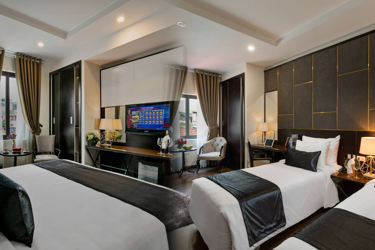 Una habitación de hotel con dos camas, un escritorio, un televisor y un espejo grande.