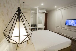 A hotel room with a bed, a hanging light fixture, a TV, and a wardrobe. - Hanoi A83 Hotel (Hanoi)