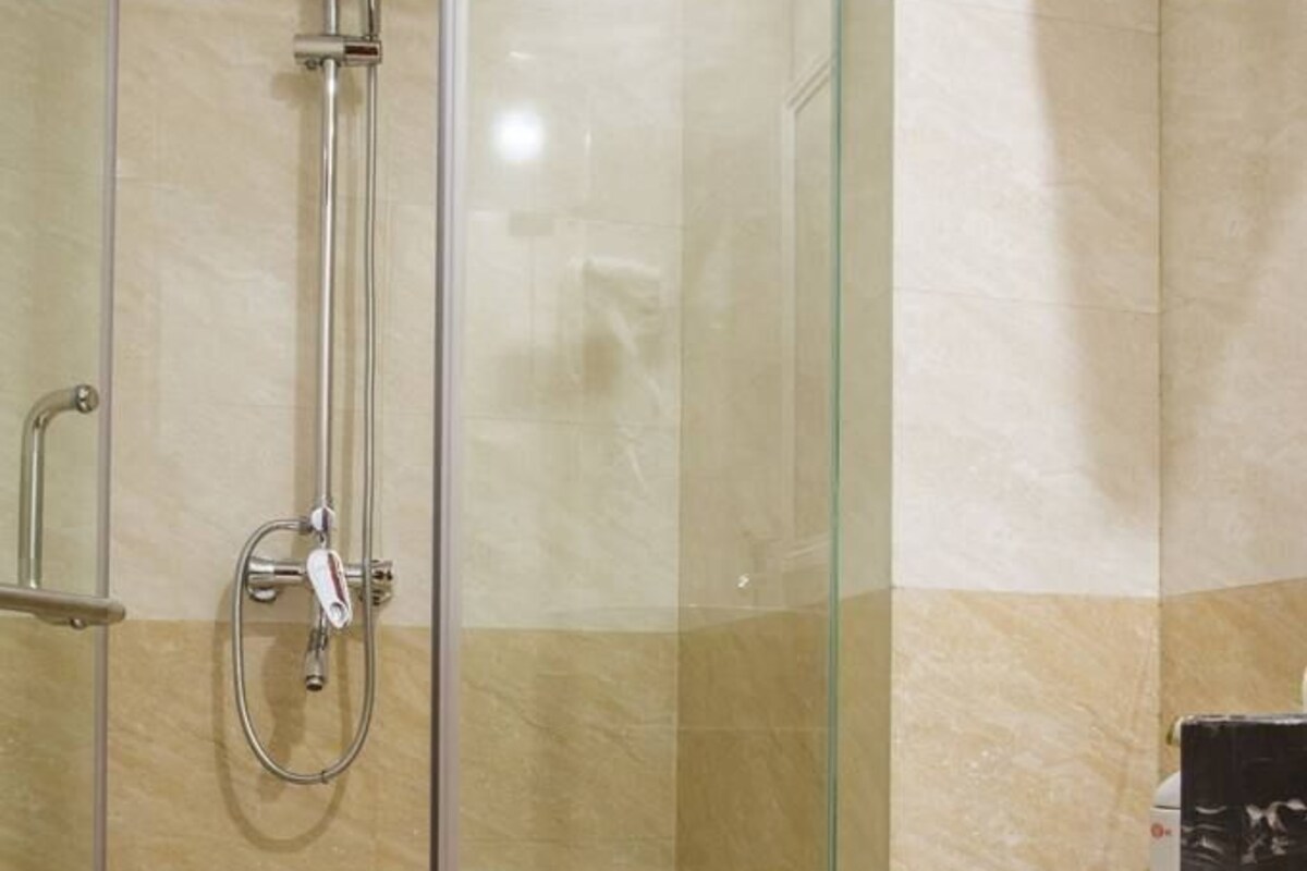 A bathroom with a glass-enclosed shower, a white toilet, and beige marble tiles.