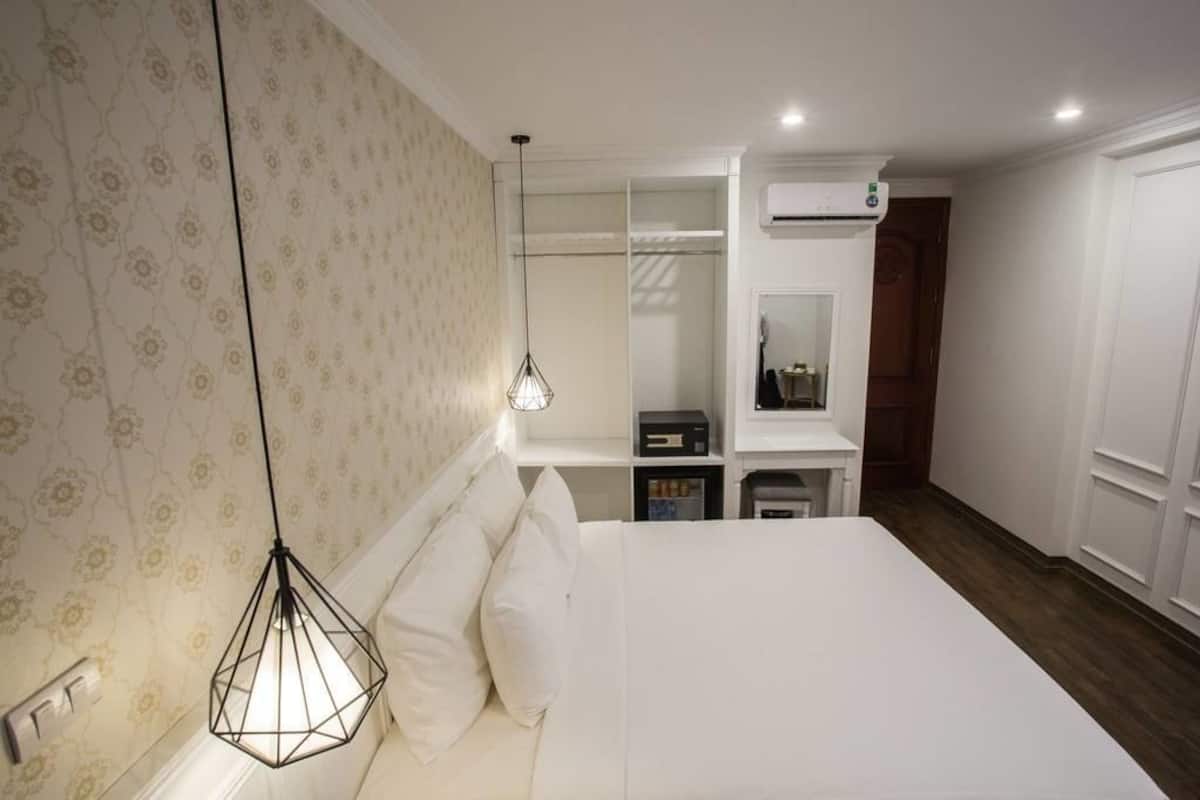Une chambre avec un lit, un luminaire suspendu, une armoire et un appareil de climatisation.