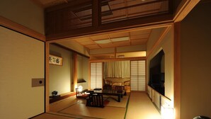 A traditional Japanese room with tatami flooring, a low table, a sofa, and sliding doors. - Kirishima Hotel (Kirishima)