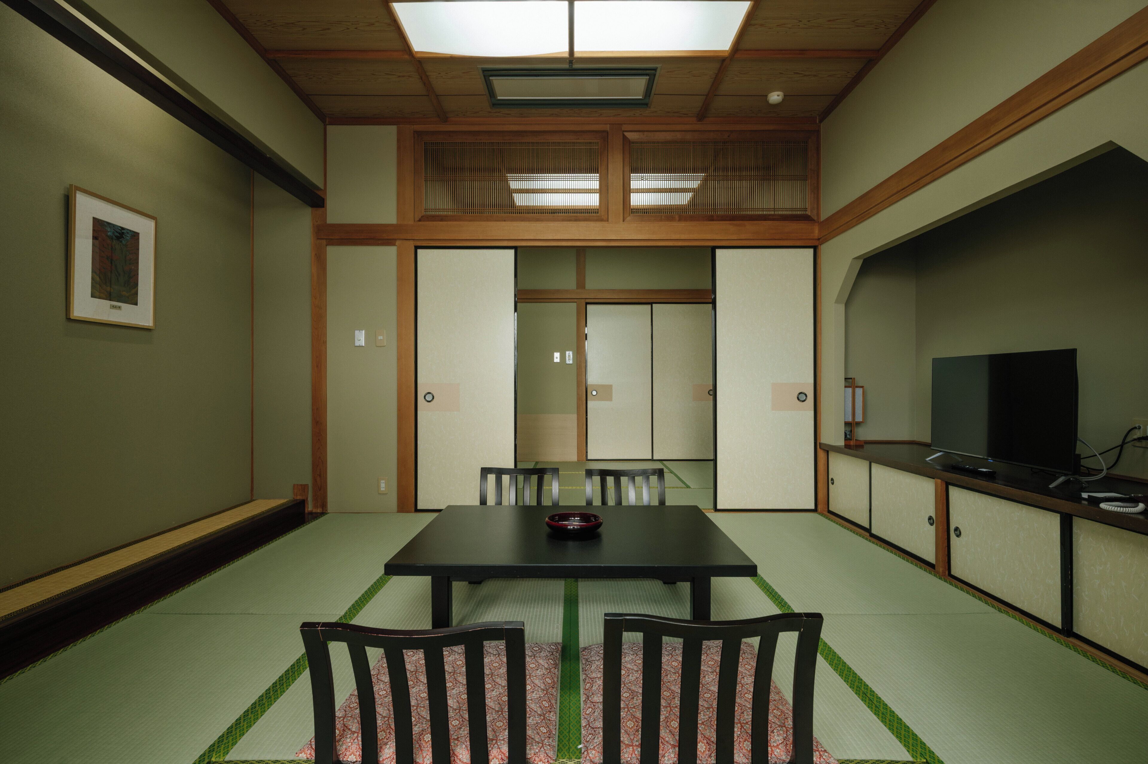 A traditional Japanese-style room with tatami flooring, a low table, and chairs.