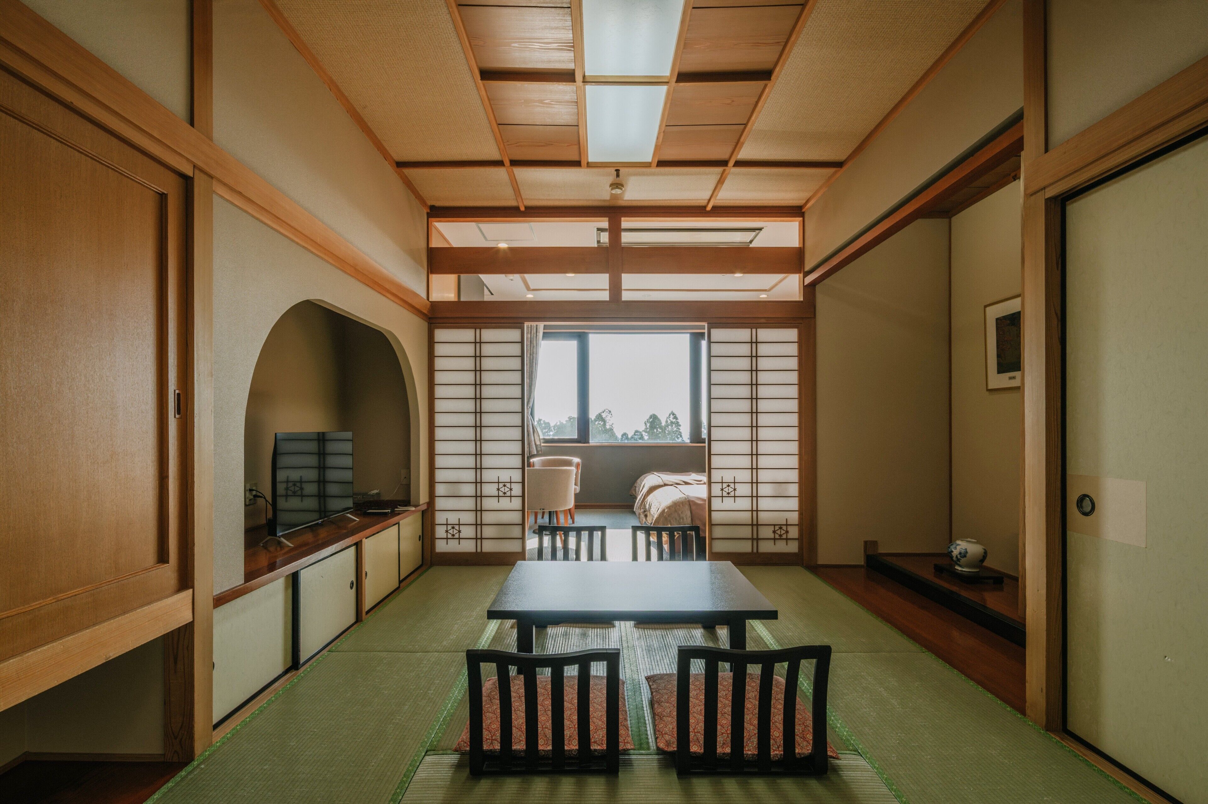 A traditional Japanese room with tatami flooring, a low table, chairs, and sliding doors.