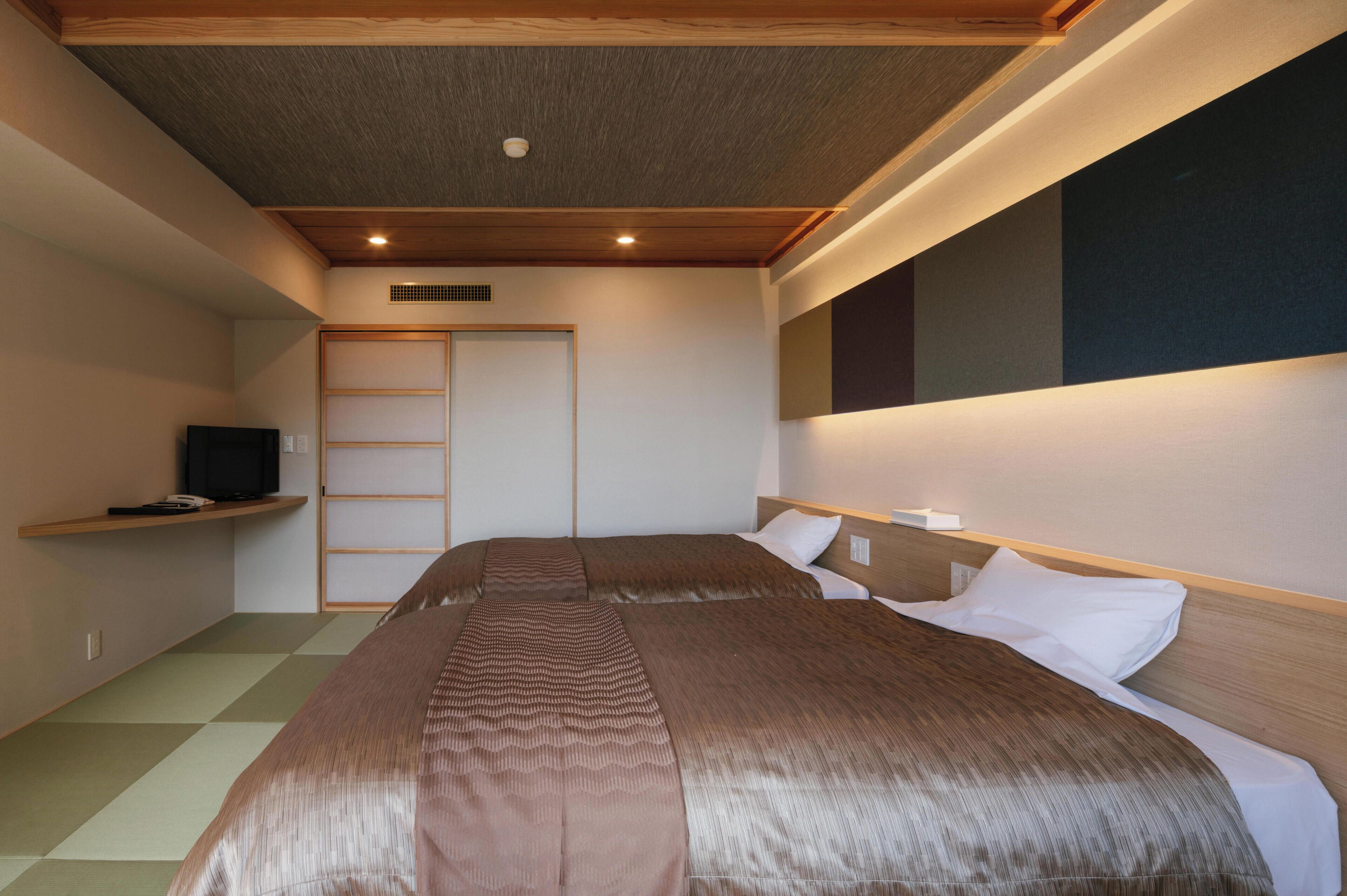 A hotel room with a bed, a television, a wardrobe, and a window.