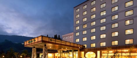 A hotel with a modern facade, multiple floors, and a covered entrance area.