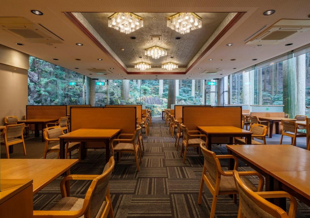 A dining area with high tables and chairs, large windows with a view of trees, and a patterned carpet.
