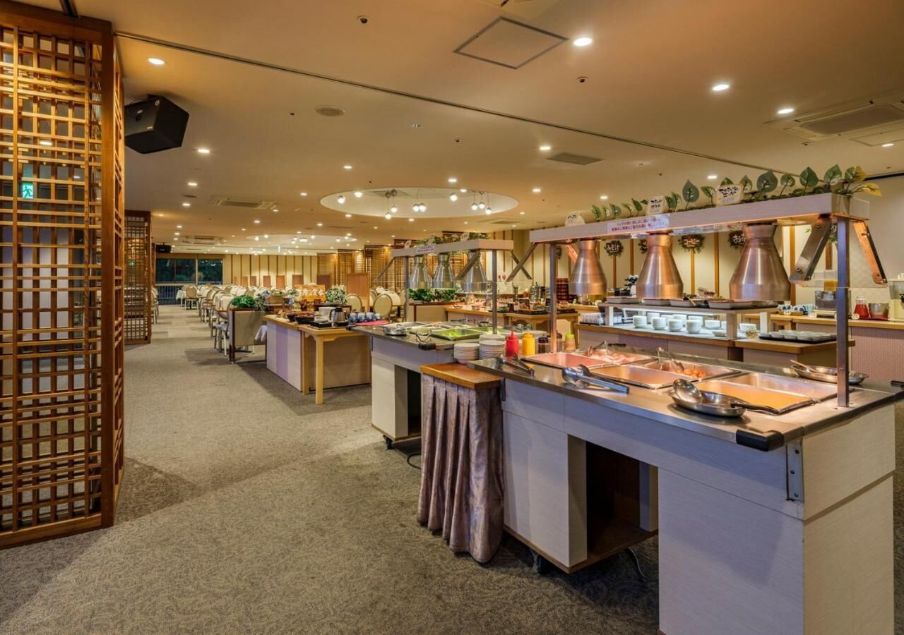 A buffet setup with multiple serving stations, a wooden partition, and a ceiling with recessed lighting.