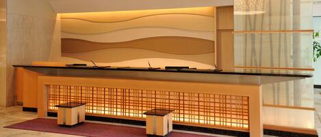 A reception desk with a modern design, featuring a wooden finish and a glass partition.