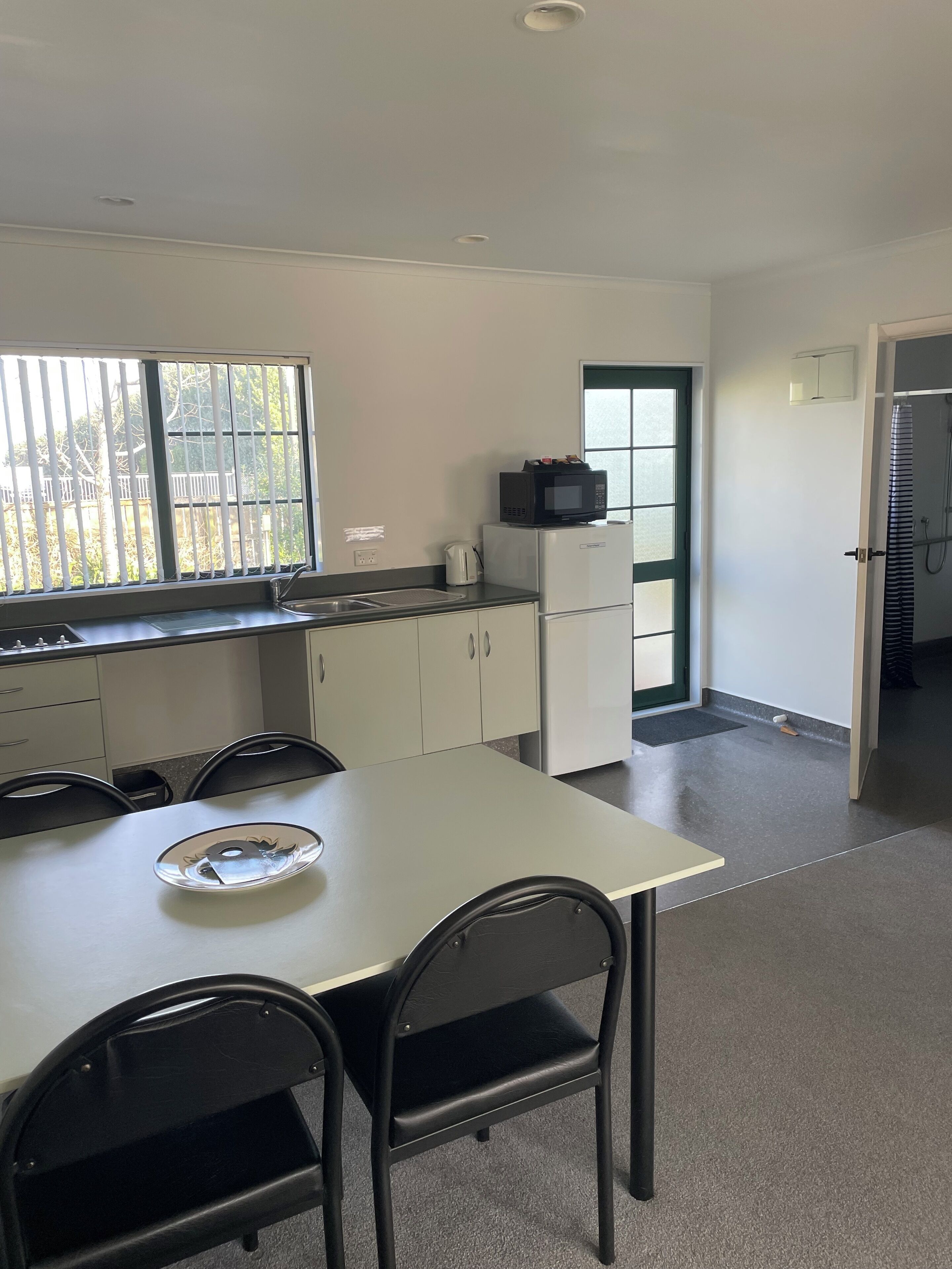 A compact kitchen with a dining table, chairs, a microwave, and a refrigerator.