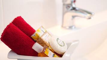 A white sink with a red towel and toiletries in a white bowl.