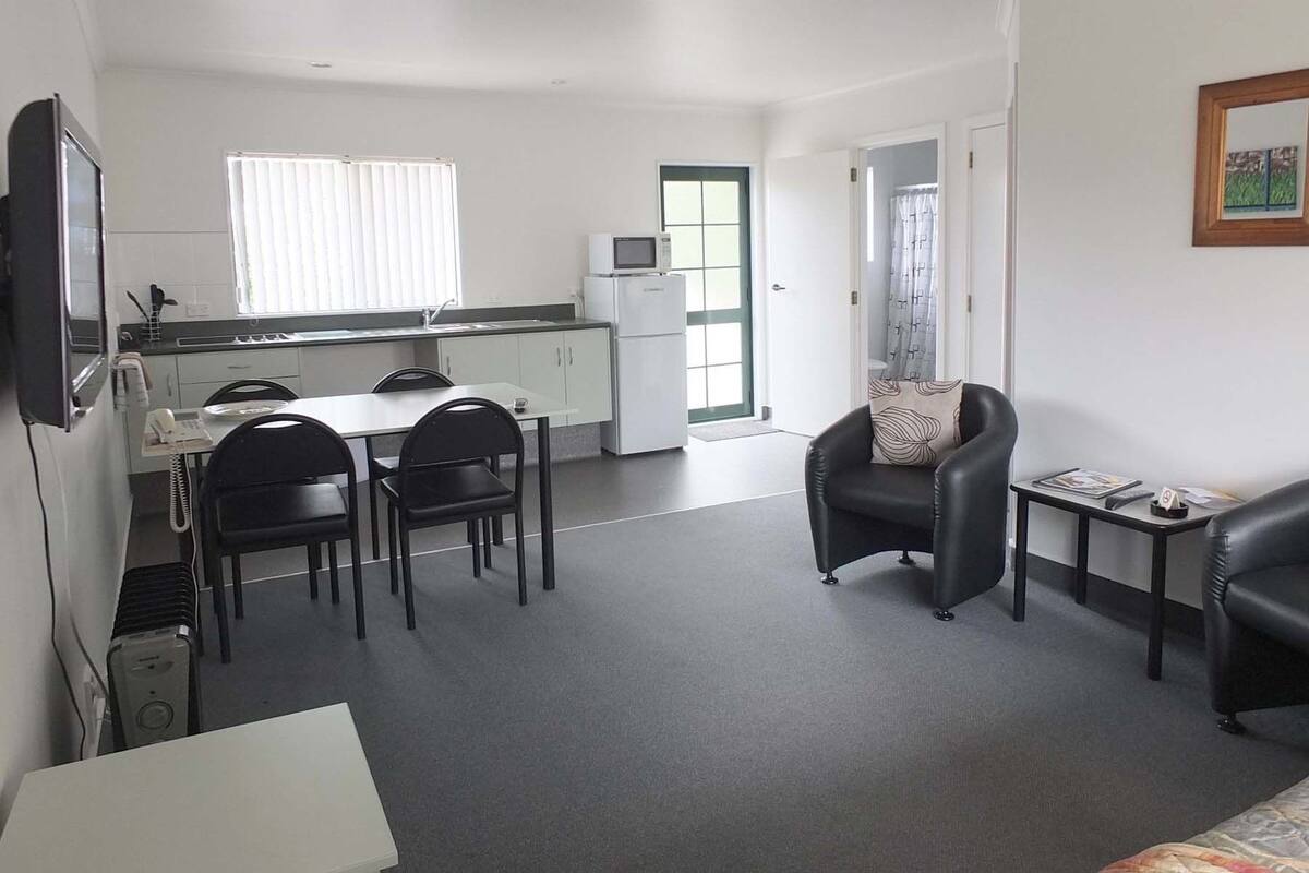 A compact living space with a kitchenette, a dining area, and a seating area with a small table and two chairs.