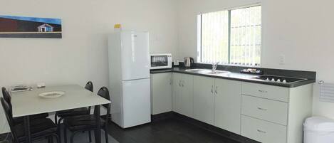 A compact kitchen with a dining area, a refrigerator, a microwave, and a window providing natural light.