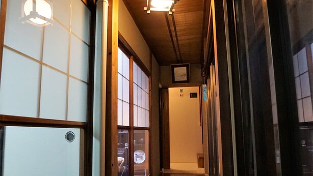 Un couloir étroit doté d’un plancher en bois, de portes coulissantes et de fenêtres de style japonais traditionnel.