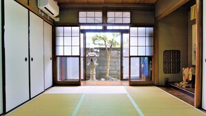Une pièce de style japonais traditionnel, avec un sol recouvert de tatamis, des portes coulissantes et une lanterne en pierre.