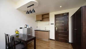 A modern kitchen with wooden cabinets, a built-in oven, and a dark wooden door. - Hotel Lexus Yangon (Yangon)