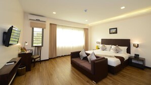 A hotel room with a bed, a sofa, a desk, a TV, and a window with curtains. - Hotel Lexus Yangon (Yangon)