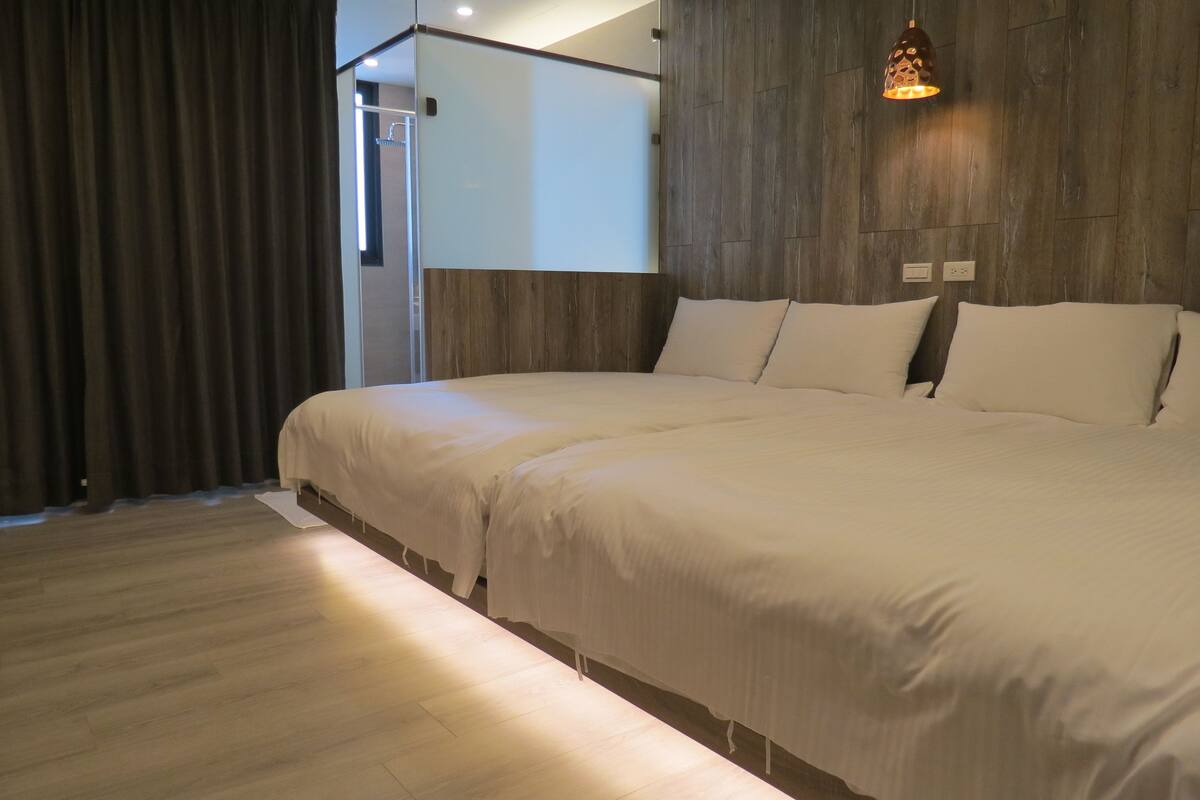 Quarto de hotel moderno com uma cama grande, painéis de parede de madeira e luminária no teto.