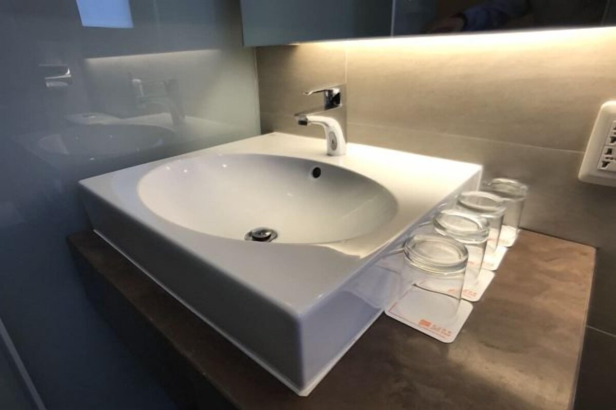 A bathroom with a white sink, a modern faucet, and a mirror above it.