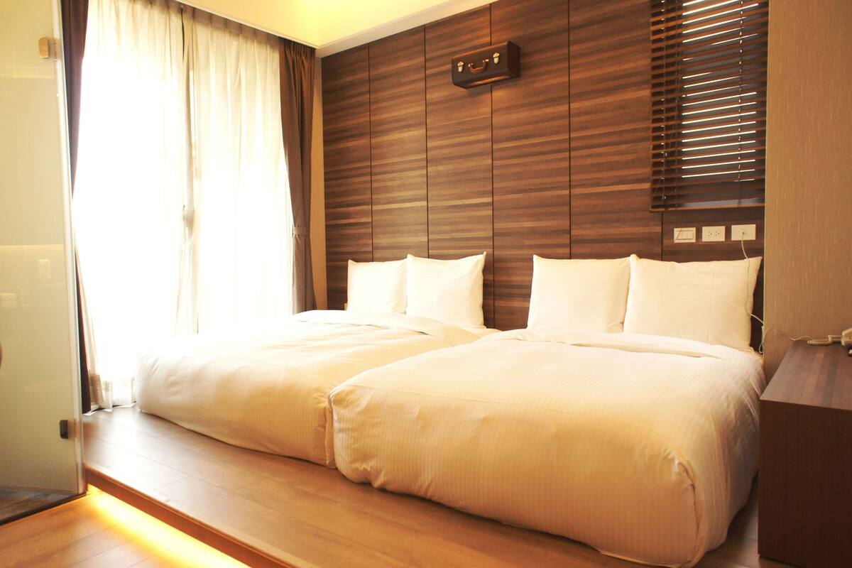 Cama de casal com lençóis brancos num quarto de hotel.