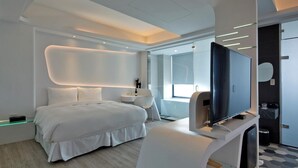Una habitación de hotel moderna con una cama grande, televisión, escritorio y baño.