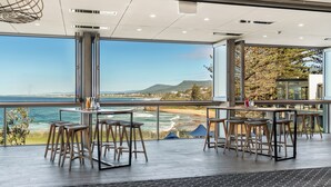 Zona de bar moderna con vistas al océano y colinas.