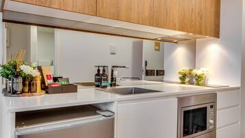 A modern kitchen with a built-in oven, a sink, and a countertop with various items.