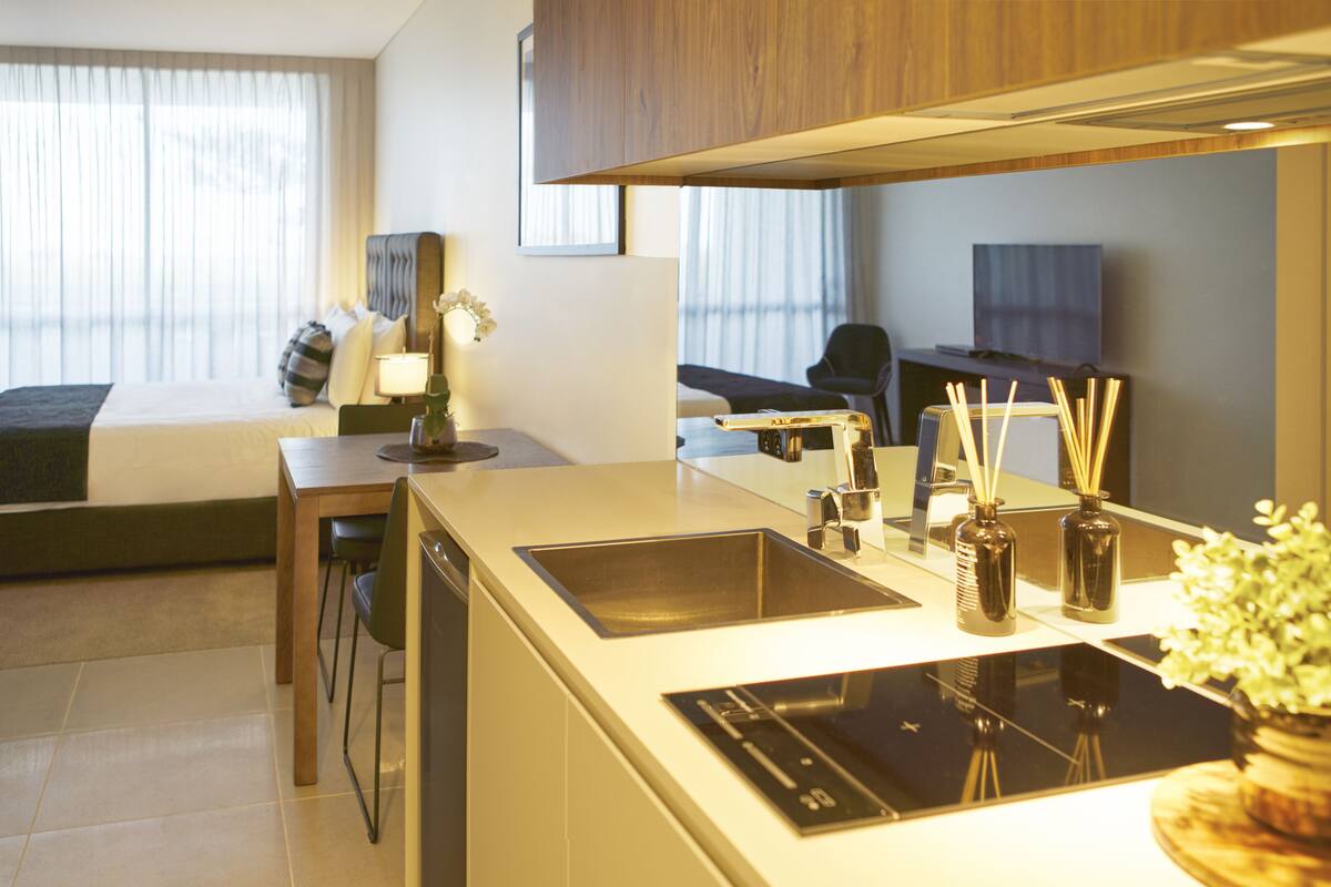 A modern kitchen with a built-in stove, a sink, and a dining area with a table and chairs.