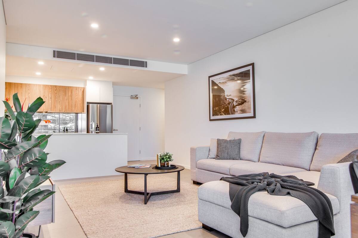 A modern living room with a grey sofa, a round coffee table, and a large painting on the wall.