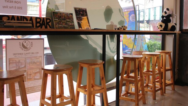 Un espace bar avec des tabourets en bois, un grand globe décoratif et des peluches en forme de panda.