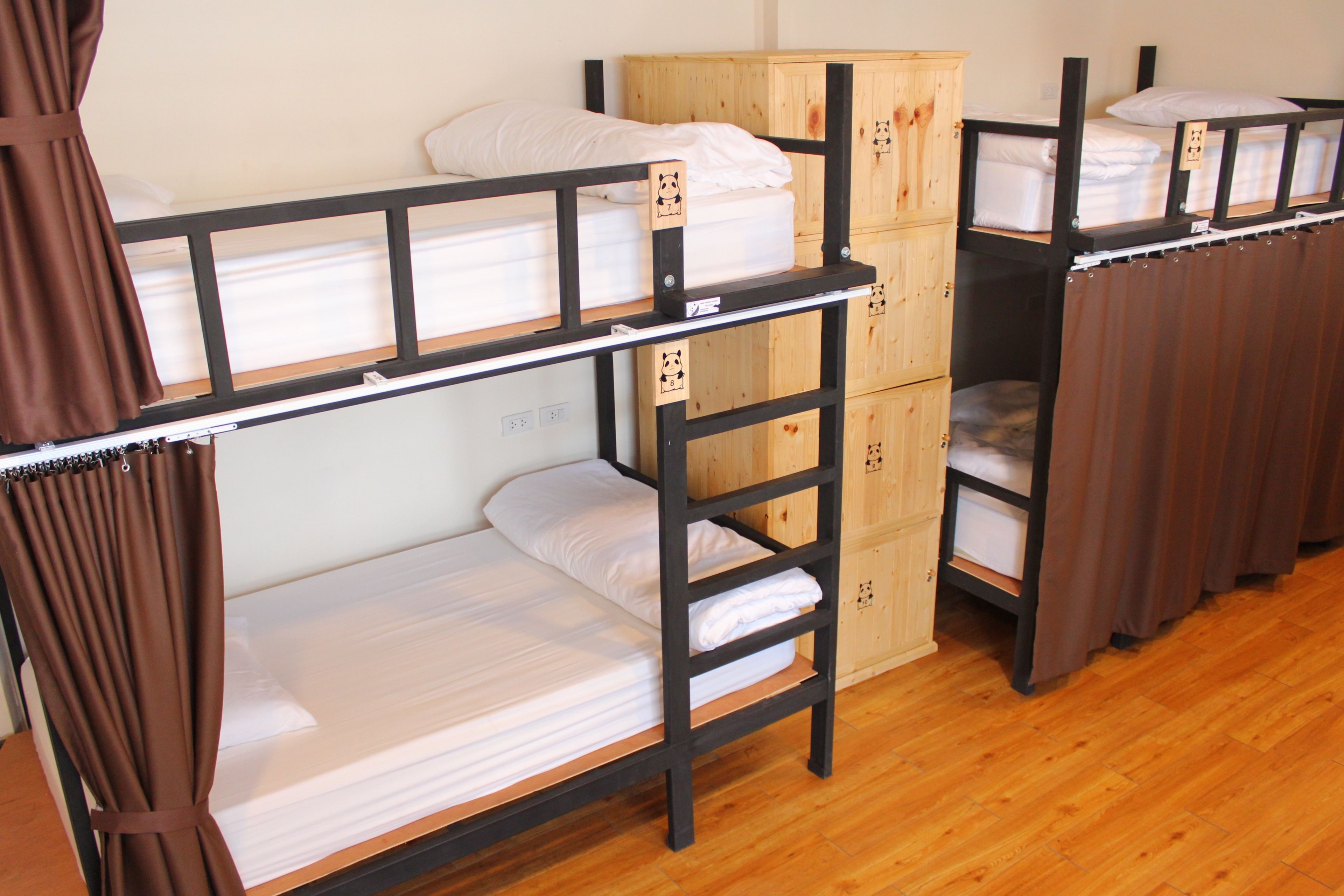 Una habitación tipo dormitorio con literas, armarios de madera y una cortina.