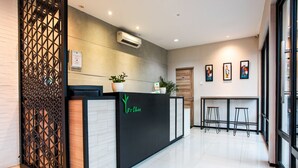 A reception desk with a modern design, including a black counter and decorative plants. - LeGreen Suite Supomo (Jakarta)