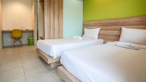 A hotel room with two single beds, a desk with a chair, and a green accent wall. - LeGreen Suite Supomo (Jakarta)