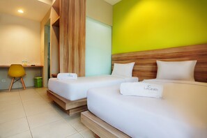 A hotel room with two beds, a wooden headboard, a green wall, and a yellow chair. - LeGreen Suite Supomo (Jakarta)