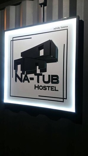 A sign for NA-TUB Hostel with a stylized bus graphic. - Na-tub Hostel (Ko Pha-ngan)