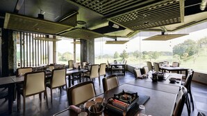 A dining area with tables and chairs, a view of the outdoors, and a modern ceiling design. - Hotel Azalea (Tsu)